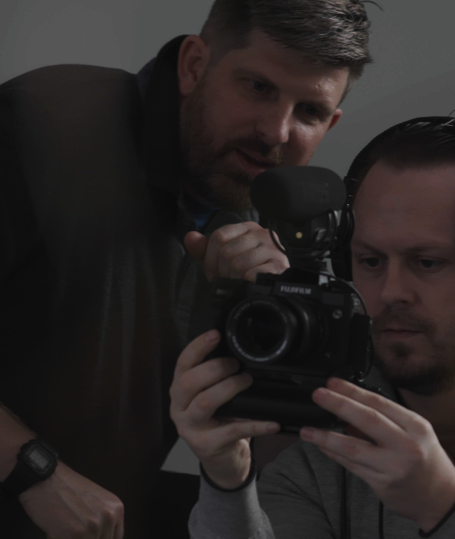 two white men looking through the lens of a camera