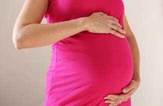 Pregnant mother touching belly. Photo zoomed in on hands and belly.