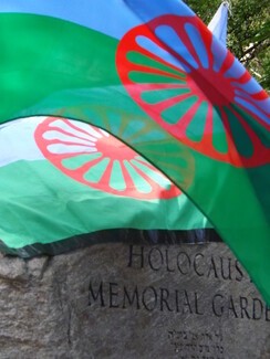 roma flags and the Holocaust memorial stone