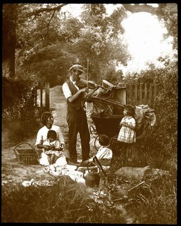Scottish Traveller man plays the fiddle outside his wooden wagon his wife, son and daughter watch