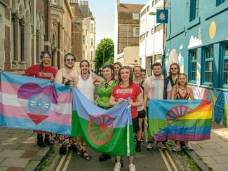 Group of GRT LGBT+ supporters from Traveller Pride holding GRT/Trans flag, GRT flag and GRT/Pride flag