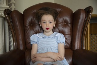 Alyssia patiently waiting for family to go to church for her brothers Holy Communion . She is 6 years old. Her mother made her feel very pretty. Big celebration.