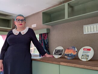 2.	Gemma in the Cold Comfort/ Kushti Shillow caravan with the plates printed with The Sun headlines and the Dale Farm eviction.