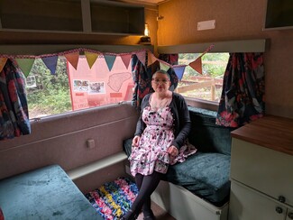 5.	Gemma in the Cold Comfort/ Kushti Shillow caravan with the bunting and proggy rug.