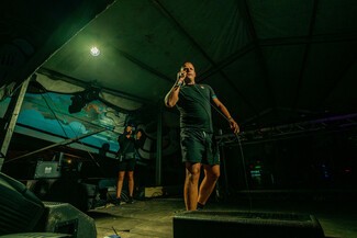 Young white male, in singing pose on stage, yellow lights