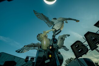 Low angle shot of a metal sculpture of three unicorns flying. 