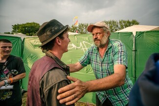 Senior looking man in green shirt speaking to middle aged man with brown shirt and burgundy waist coat