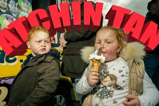 Billboard design of two young children left child in black looking and right child in white eating ice cream cone. Words above says "Atchin Tan".